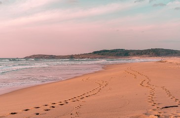 Playa idílica y solitaria en otoño con línea de huellas sobre la arena