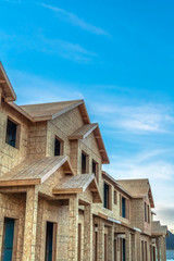 Construction of townhouses viewed against blue sky and clouds on a sunny day