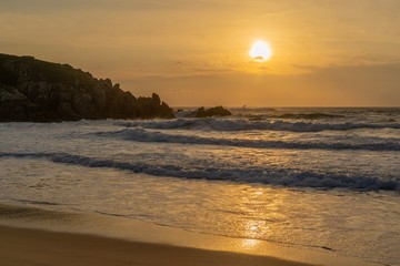 Puesta de Sol con olas sobre acantilado rocoso