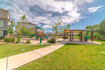 Park at a sunny neighborhood with childrens playground and pavilion eating area