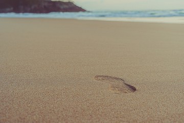 Una huella en primer plano sobre la arena r virgen de una playa solitaria e idílica