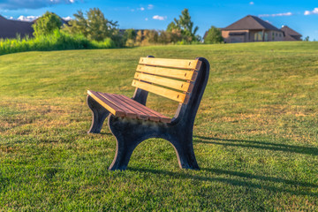Focus on an empty outdor bench against short green grasses on a sunny day