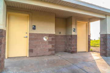 Public restroom at a golf course with white doors and concerete and brick wall