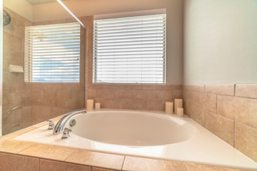 Close up of circular built in bathtub in front of window inside a home bathroom