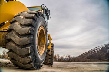 Focus on the black rubber tires of a yelow bulldozer at a construction site