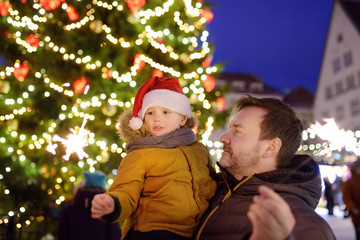 Little boy and his father with sparklers near giant Christmas fir tree on fair in Tallinn, Estonia.