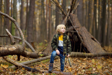 Little boy scout with spyglass during hiking in autumn forest. Child is looking through a spyglass.