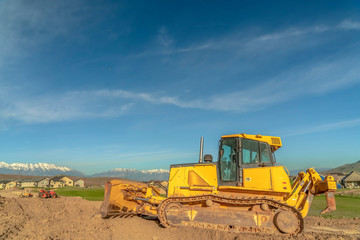 Yellow bulldozer with tracks and a blade used for pushing construction materials