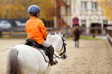 Girls rider trains in horse riding in equestrian club on autumn day.