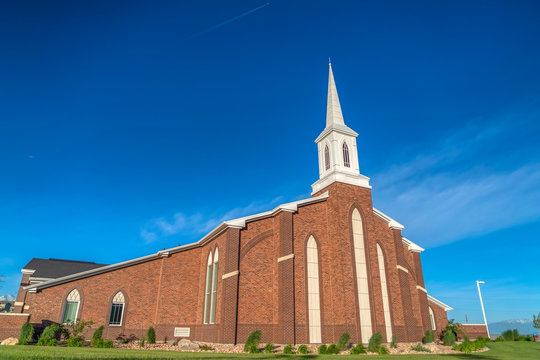 Sunny day view of a church with white steeple and vibrant blue sky background