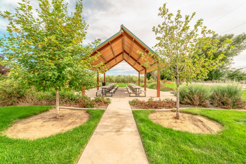 Beautiful view of a picnic pavilion at a park with pathway and trees in front