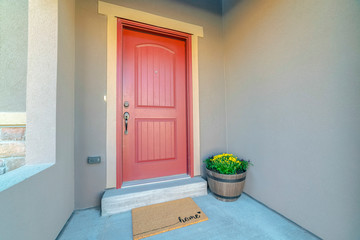 Red wooden front door at the entrance of a home with concrete exterior wall