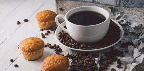 Close up still life, cup of coffee with muffins. Freshly baked delicious muffins and cup of coffee on wooden table. Cup of fresh aromatic coffee and cupcake at table in cafe.