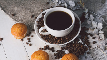 Close up still life, cup of coffee with muffins. Freshly baked delicious muffins and cup of coffee on wooden table. Cup of fresh aromatic coffee and cupcake at table in cafe.