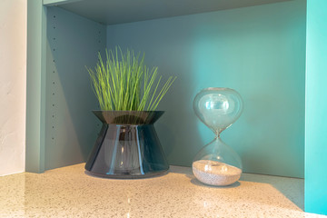 Stylish grass plant and sand timer on bench