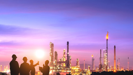 The silhouette of the engineering team is working at the oil and gas refinery in a large energy industrial zone at sunset
