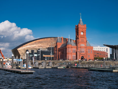 A view across Cardiff Bay in Cardiff, Wales, UK on a sunny day in Autumn - the copper roof of the Wales Millennium Centre and the red brick of the Grade 1 listed Pierhead Building are visible.