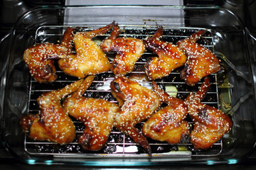Baked teriayki chicken wings from the oven resting on the stove top in a home kitchen.