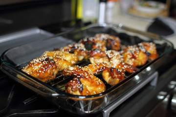 Baked teriayki chicken wings from the oven resting on the stove top in a home kitchen.