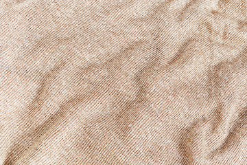 Texture of knitted fabric background. Close up clothing beige gold color. Textiles of autumn shades.