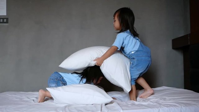 Naughty children little girls staged a pillow fight on the bed in the bedroom. Family time on vacation day.