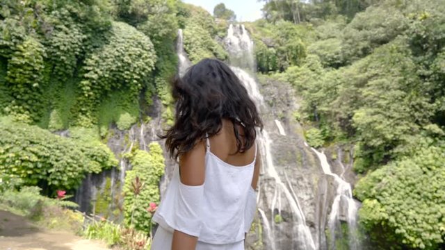 stylish young asian woman taking picture for social media in beautiful waterfall