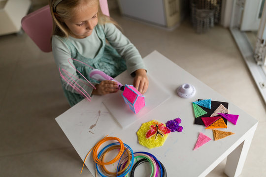Cute little girl makes a plastic house, draws parts with a 3D pen. STEM and STEAM education. Development, modeling, education, design with hot plastic. Modern technologies. DIY.