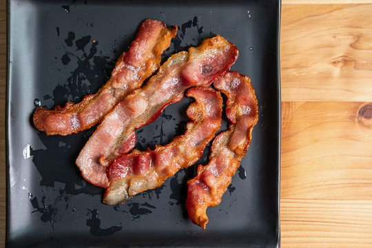 Crispy fried bacon on black plate, Unhealthy food