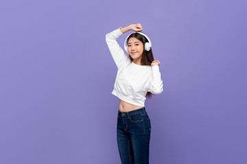 Asian woman wearing wireless headphones listening to music and dancing