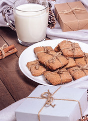 A cup of milk, cinnamon sticks and homemade cookies in a Christmas decor.