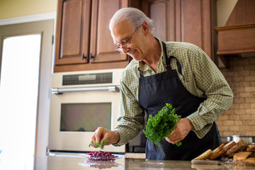 Fototapeta premium Good looking senior man holding parsley garnishing fresh made cranberries