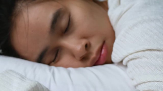 Asian young woman snoring on soft white pillow in bed. Health care concept.