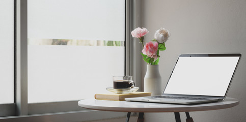 Modern workspace with laptop computer and flowers decorations on white table