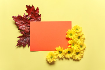 Sheet of paper with autumn leaves and flowers on color background