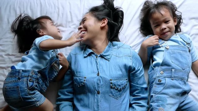 Happy Asian family lying on the bed in the morning. Vacation relaxed time of family.