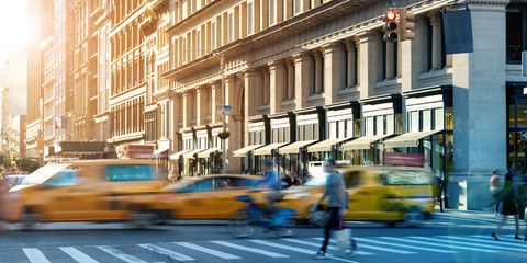 Busy street scene in Midtown Manhattan with taxis and people hurrying through the crowded intersection on 23 St and 5th Avenue in New York City