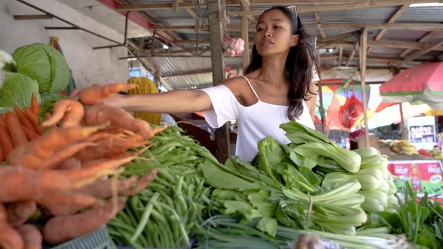 portrait of young attractive exotic asian woman while in the market buying some vegetable