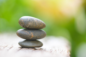 Obraz na płótnie Canvas Natural wellness concept - Relax zen stones stack on wooden nature green background Spa Natural Alternative Therapy With Massage Stones