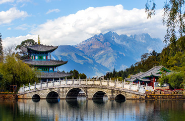 Beautiful view of the Jade Dragon Snow Mountain and the Suocui Bridge over the Black Dragon Pool in the Jade Spring Park, Lijiang, Yunnan