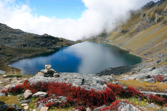 Clear Gosaikunda Mountain Lake, With Red Flowers In Foreground, Nepal, September 2019