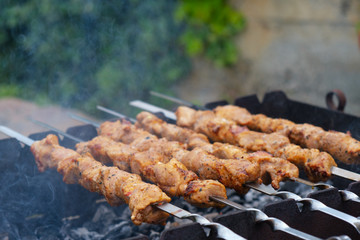 Shish kebab roasting on the grill. BBQ party. Close-up. Marinated shashlik preparing on a barbecue grill over charcoal.