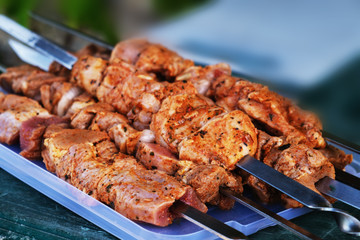 Fresh pickled meat with seasonings on skewers. On a blue tray.