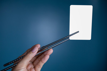 Hold holding chopsticks on a blank piece of paper. Close up White business card.