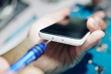 Repairman using pentalob screwdriver to remove screws on the smartphone bottom edge
