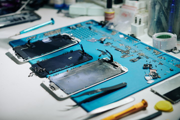 Parts and details of disassembled smartphone on desk of repairman