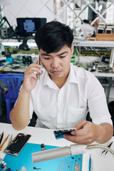 Confused repairman calling coworker when having some problems with fixing smartphone for customer