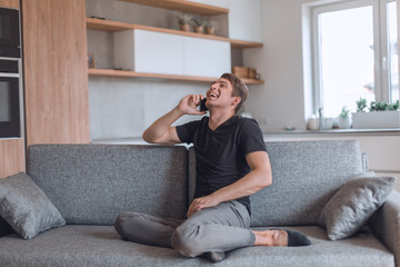 Obraz premium smiling young man talking on his smartphone