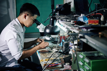 Repairman using microscope when fixing small details in smartphone