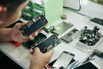 Fototapeta na wymiar Close-up image of repairman examining smartphones before fixing them