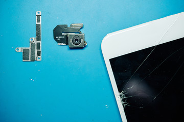 Broken camera and metal bracket next to cracked smartphone screen